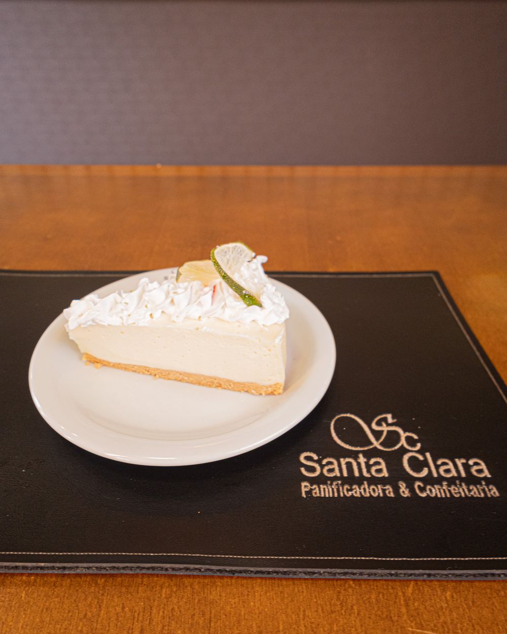 Fatia de torta de limão com cobertura de merengue sobre o jogo americano da Santa Clara